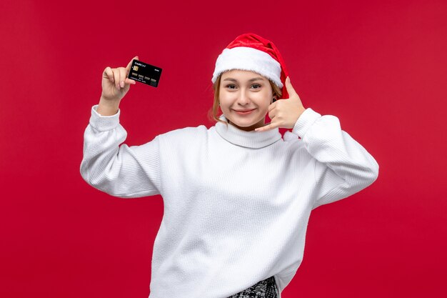 Вид спереди молодая женщина, держащая банковскую карту на красном фоне