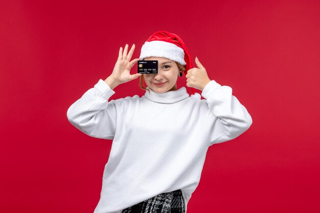 Front view young woman holding bank card on red background