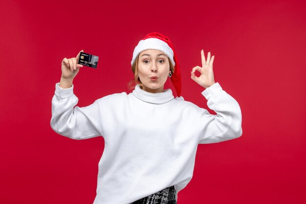 Front view young woman holding bank card on a red background