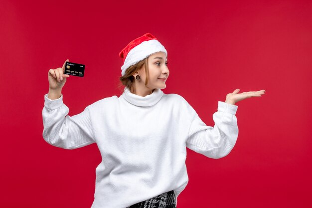 Front view young woman holding bank card on red background