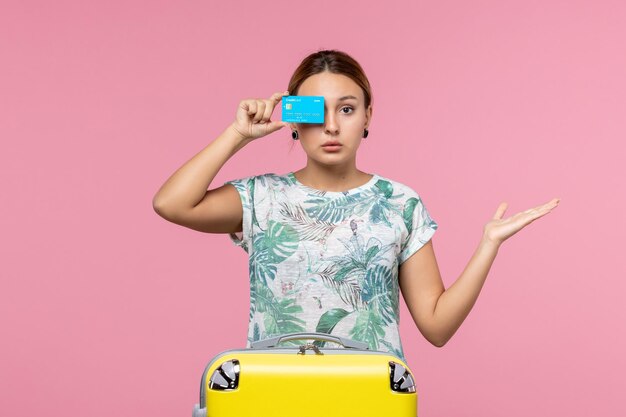 Вид спереди молодая женщина, держащая банковскую карту с желтой сумкой на розовой стене самолета, отдых, рейс, путешествие, женщина, отдых