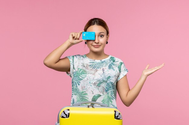 Вид спереди молодая женщина, держащая банковскую карту с желтой сумкой на розовой стене самолета, отдых, рейс, путешествие, женщина, отдых