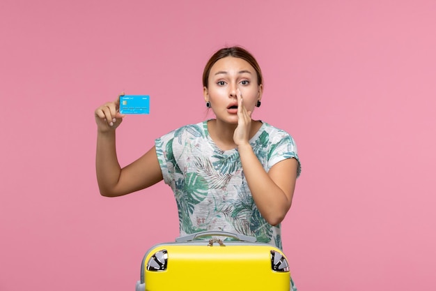 Free photo front view young woman holding bank card with yellow vacation bag on the light-pink wall rest flight voyage plane woman