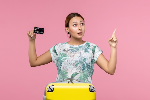 밝은 분홍색 벽 비행기 휴가 비행 항해 여자 휴식에 검은 은행 카드를 들고 전면 보기 젊은 여자