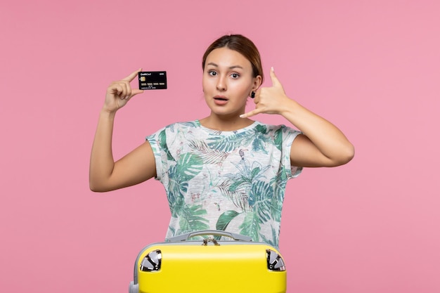 Vista frontale della giovane donna che tiene la carta di credito nera sul muro rosa