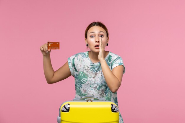 Front view of young woman holding brown bank card and whispering on pink wall