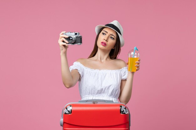 Front view young woman holding camera and cocktail on the pink wall color vacation trip heat summer voyage