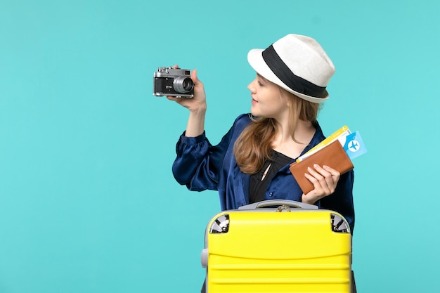 Free photo front view young woman holding camera and tickets on a blue background woman journey sea travelling voyage plane