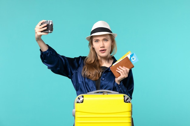 Front view young woman holding camera and tickets on blue background woman journey sea travelling voyage plane