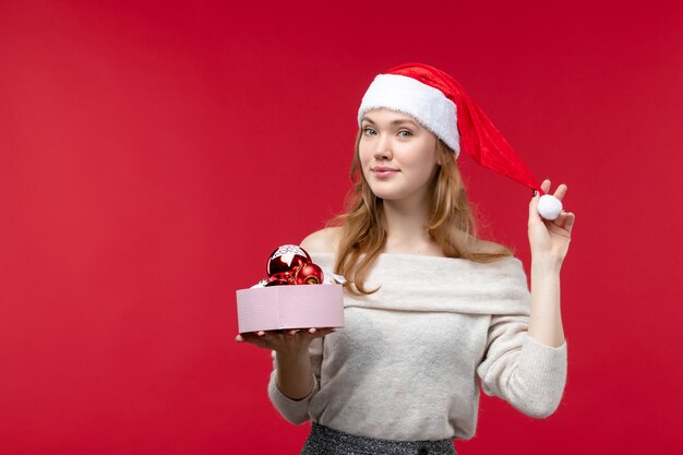 Front view of young woman holding christmas toys on red