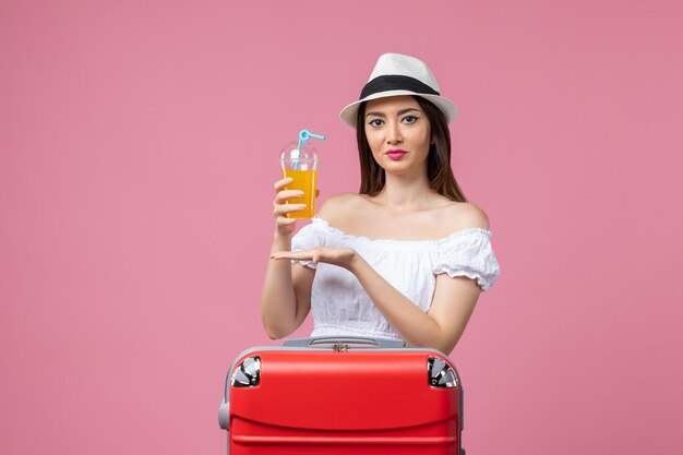 Front view young woman holding cocktail with red vacation bag on pink wall emotion vacation plane voyage summer trip