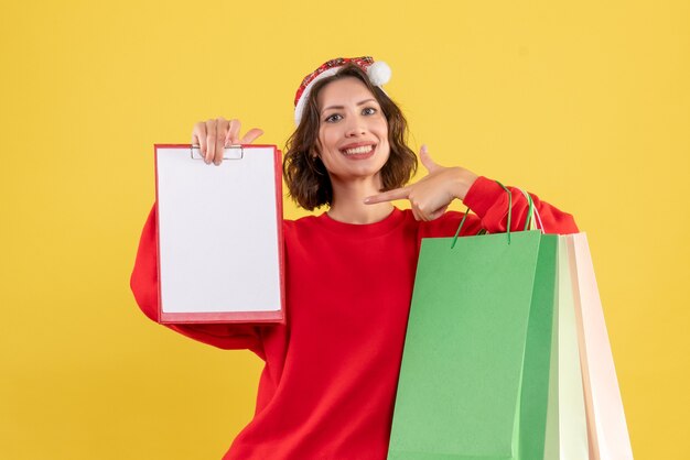 Front view young woman holding file note and packages on yellow