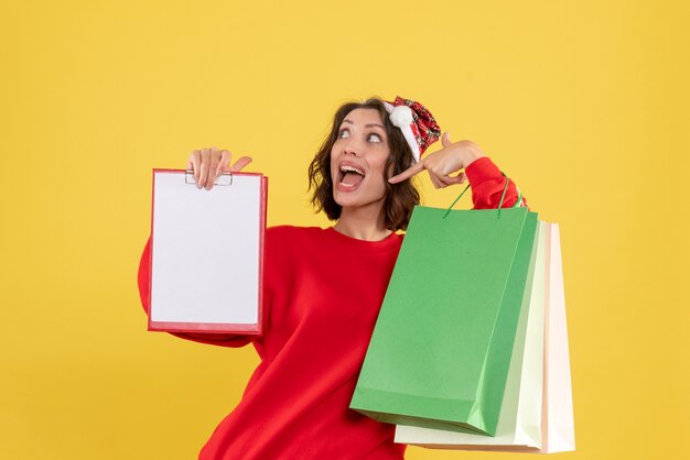 Front view young woman holding file note and packages on yellow