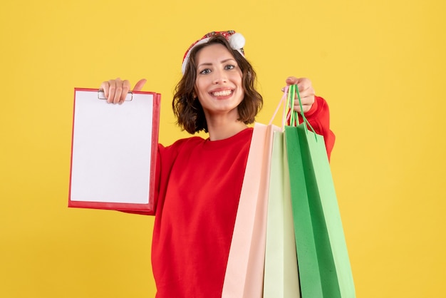 Front view young woman holding file note and packages on yellow