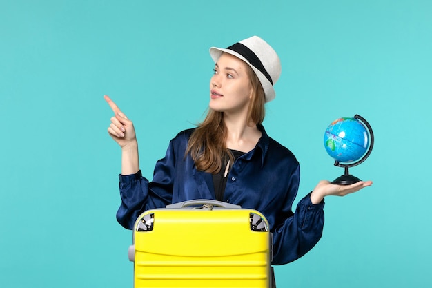 Front view young woman holding globe and preparing for vacation on blue background female vacation journey voyage sea plane