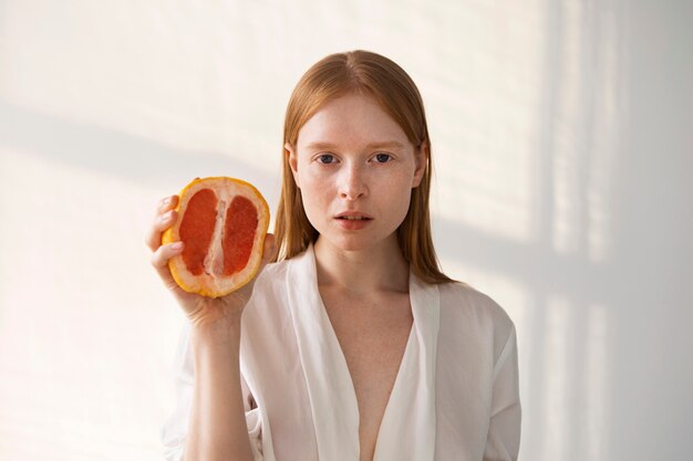 Front view young woman holding grapefruit