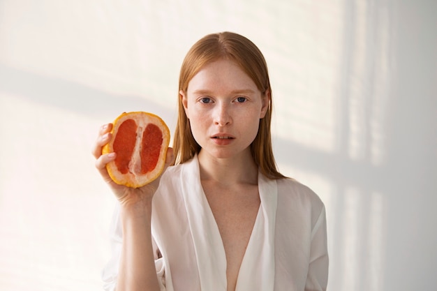 Front view young woman holding grapefruit