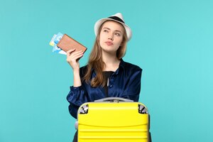 front view young woman holding her tickets and preparing for trip on the blue background journey plane sea vacation travel voyage