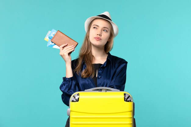 Front view young woman holding her tickets and preparing for trip on the blue background journey plane sea vacation travel voyage