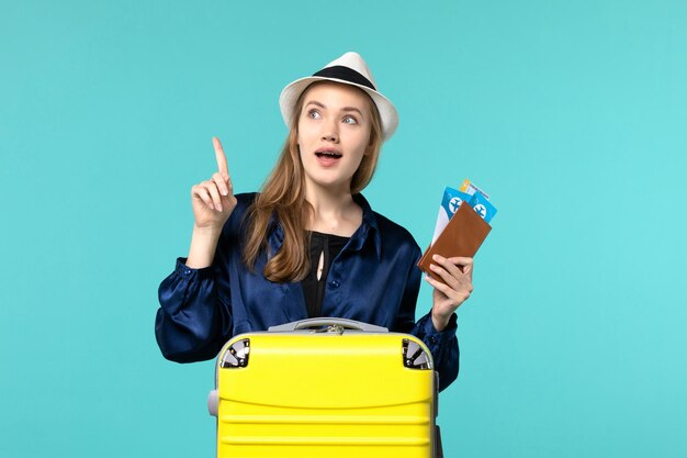 彼女のチケットを保持し、青い背景の旅航海飛行機海の休暇旅行で旅行の準備をしている正面図若い女性