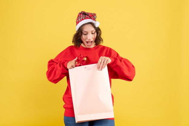 Front view young woman holding little present on yellow