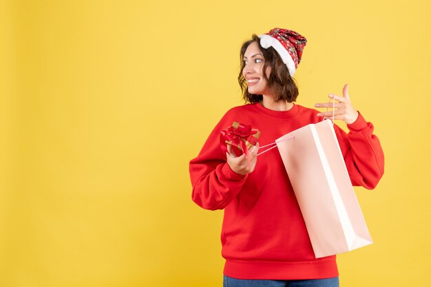 Front view young woman holding little present on yellow