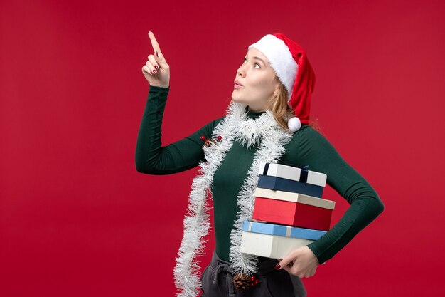 Front view young woman holding new year presents on red background