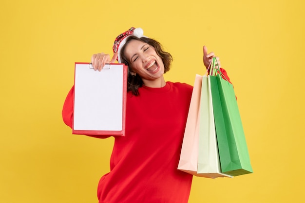 Free photo front view young woman holding packages and file note on yellow