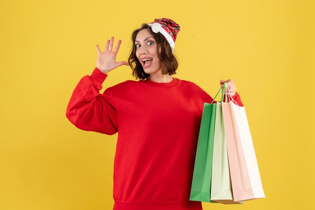 Front view young woman holding packages from shopping on yellow