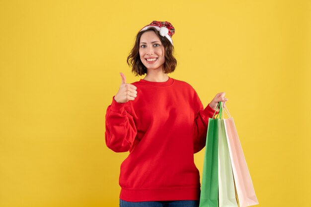 Front view young woman holding packages from shopping on yellow