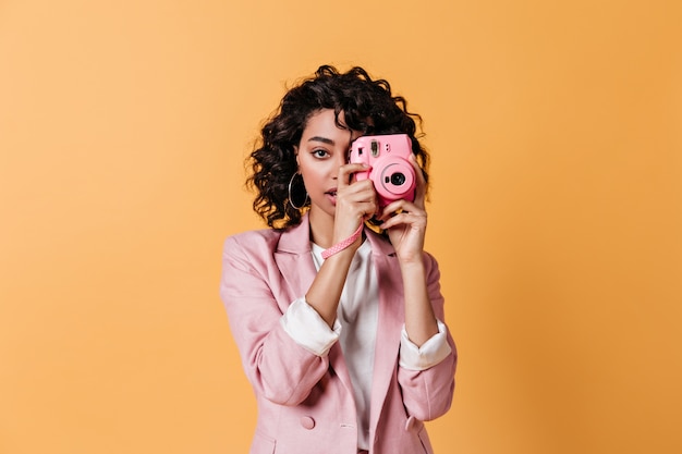 ピンクのカメラを保持している若い女性の正面図