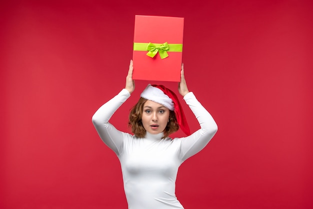 Free photo front view of young woman holding present on red