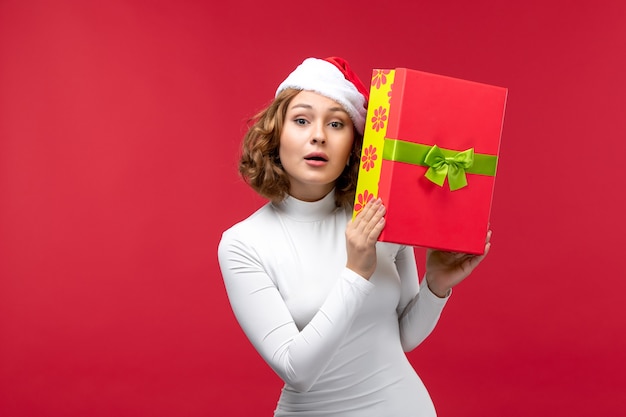 Front view of young woman holding present on red