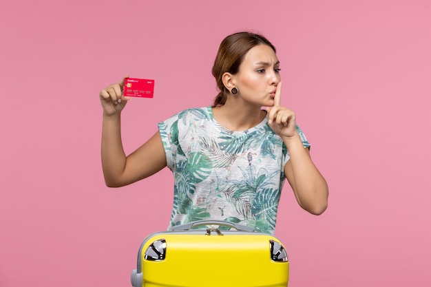 Front view young woman holding red bank card on pink wall flight woman voyage plane rest