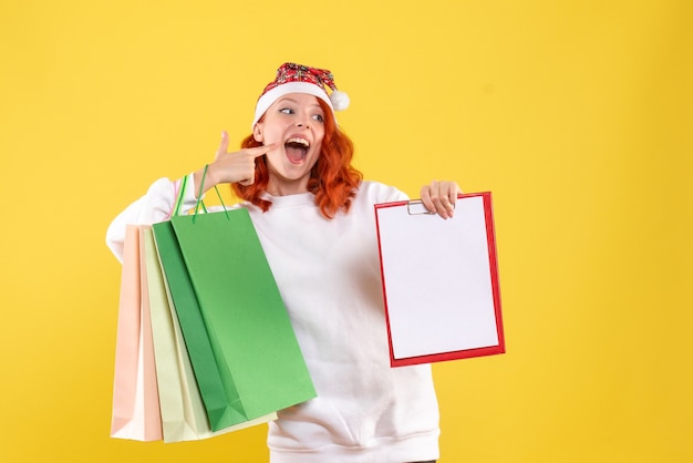 Free photo front view of young woman holding shopping packages on the yellow wall