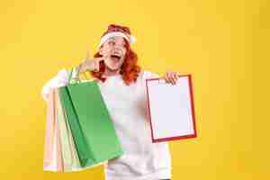 Free photo front view of young woman holding shopping packages on the yellow wall