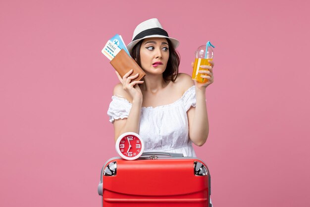 Front view young woman holding tickets and cocktail on vacation on pink floor trip woman vacation voyage summer heat