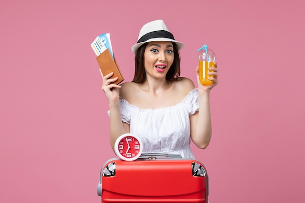 Front view young woman holding tickets and cocktail on vacation on a pink wall woman vacation voyage trip summer heat