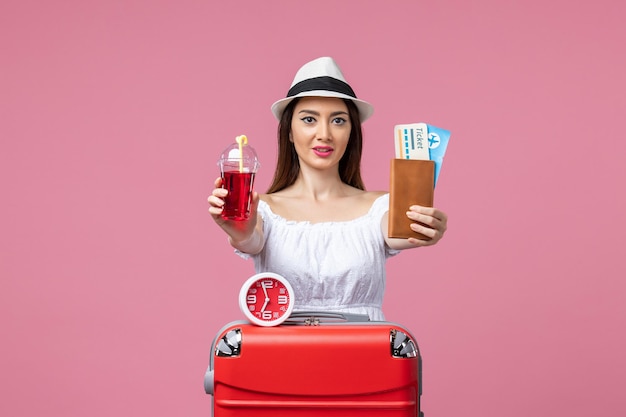 Front view young woman holding tickets and juice on vacation on a pink wall voyage trip summer woman