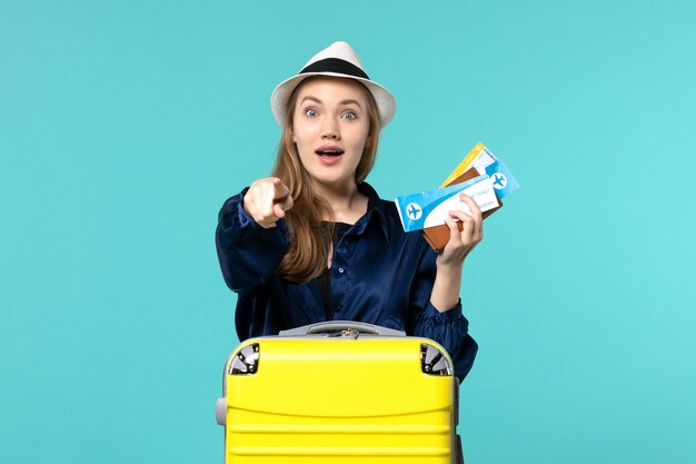 Front view young woman holding tickets and preparing for trip being excited on a blue background sea journey voyage plane vacation