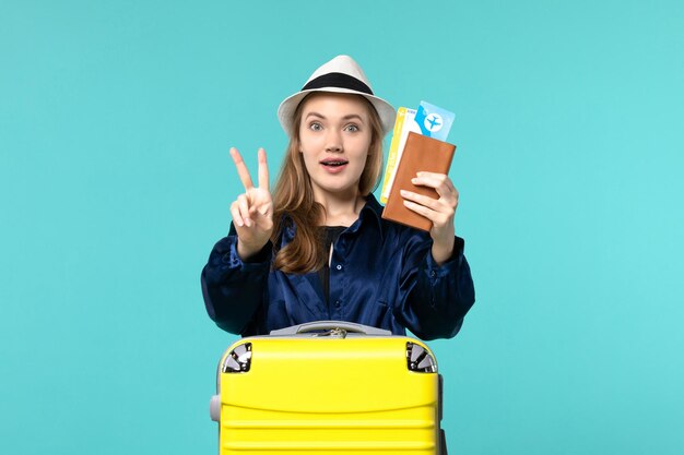 Front view young woman holding tickets and preparing for trip on blue desk journey sea vacation travel plane voyage