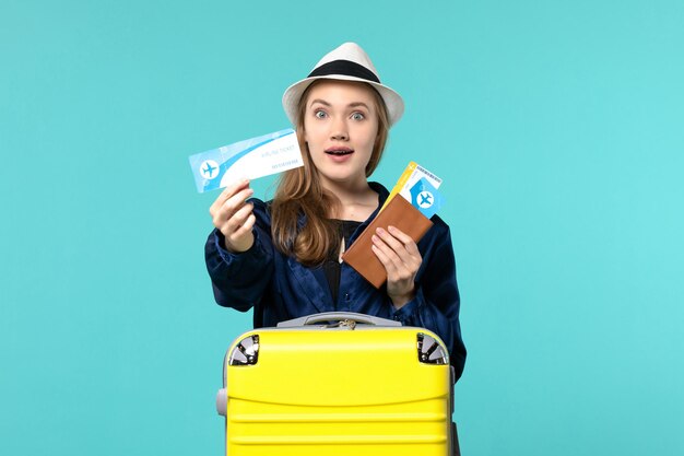 Front view young woman holding tickets and preparing for vacation on blue background female journey voyage sea plane vacation