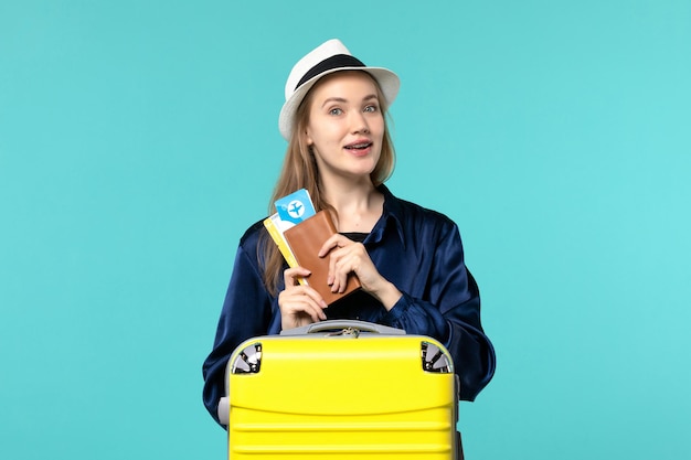 チケットを保持し、青い背景の飛行機の旅海の休暇の航海旅行で休暇の準備をしている正面図の若い女性