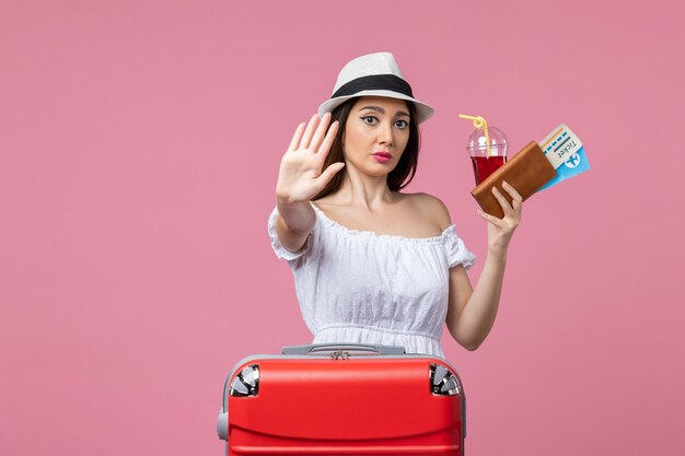 Front view young woman holding tickets on vacation on light pink wall summer voyage woman trip rest