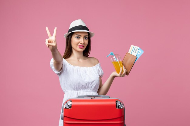 Front view young woman holding tickets for vacation and posing on pink wall summer trip emotions plane voyage