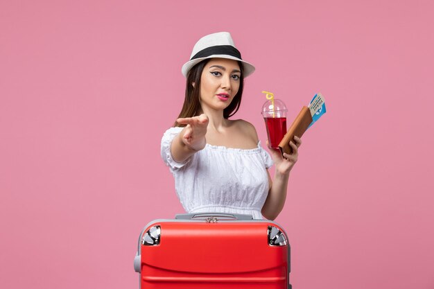 Front view young woman holding tickets with juice on vacation on a light-pink wall summer voyage woman trip rest