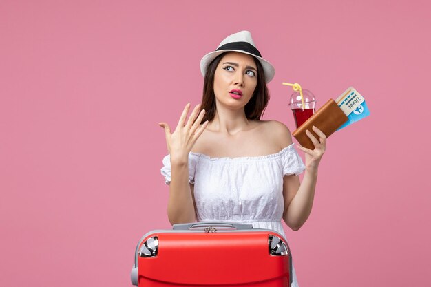 Front view young woman holding tickets with juice on vacation on the pink wall summer voyage woman trip rest