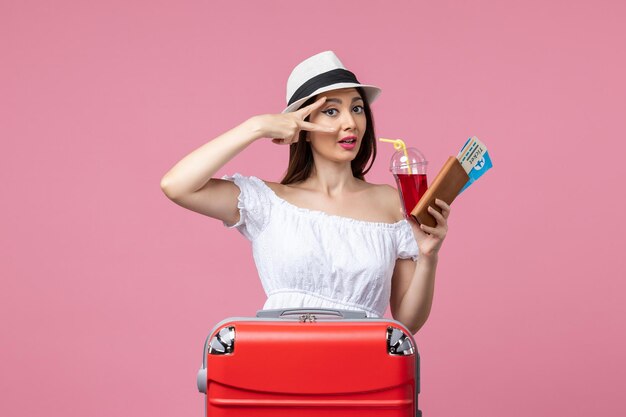 Front view young woman holding tickets with juice on vacation on pink wall woman summer trip rest voyage