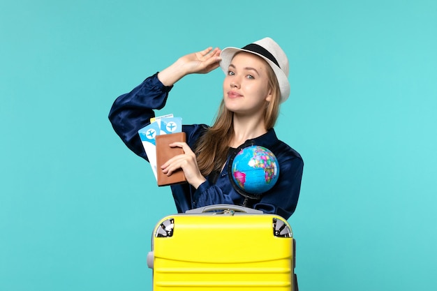 Front view young woman holding wallet with tickets on the blue background plane voyage woman journey sea vacation