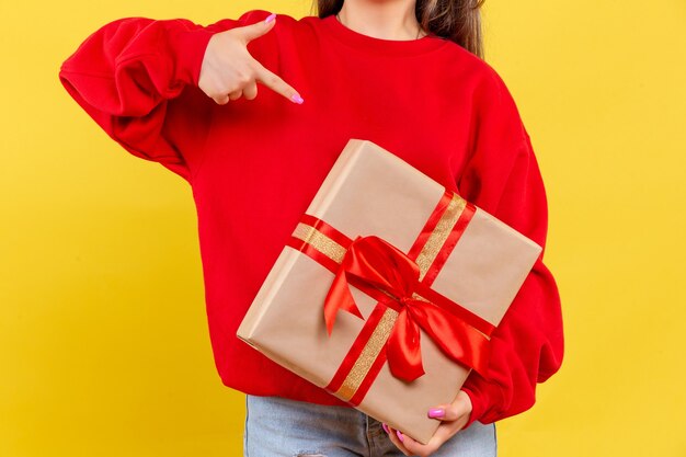 Front view young woman holding xmas gift on a yellow background